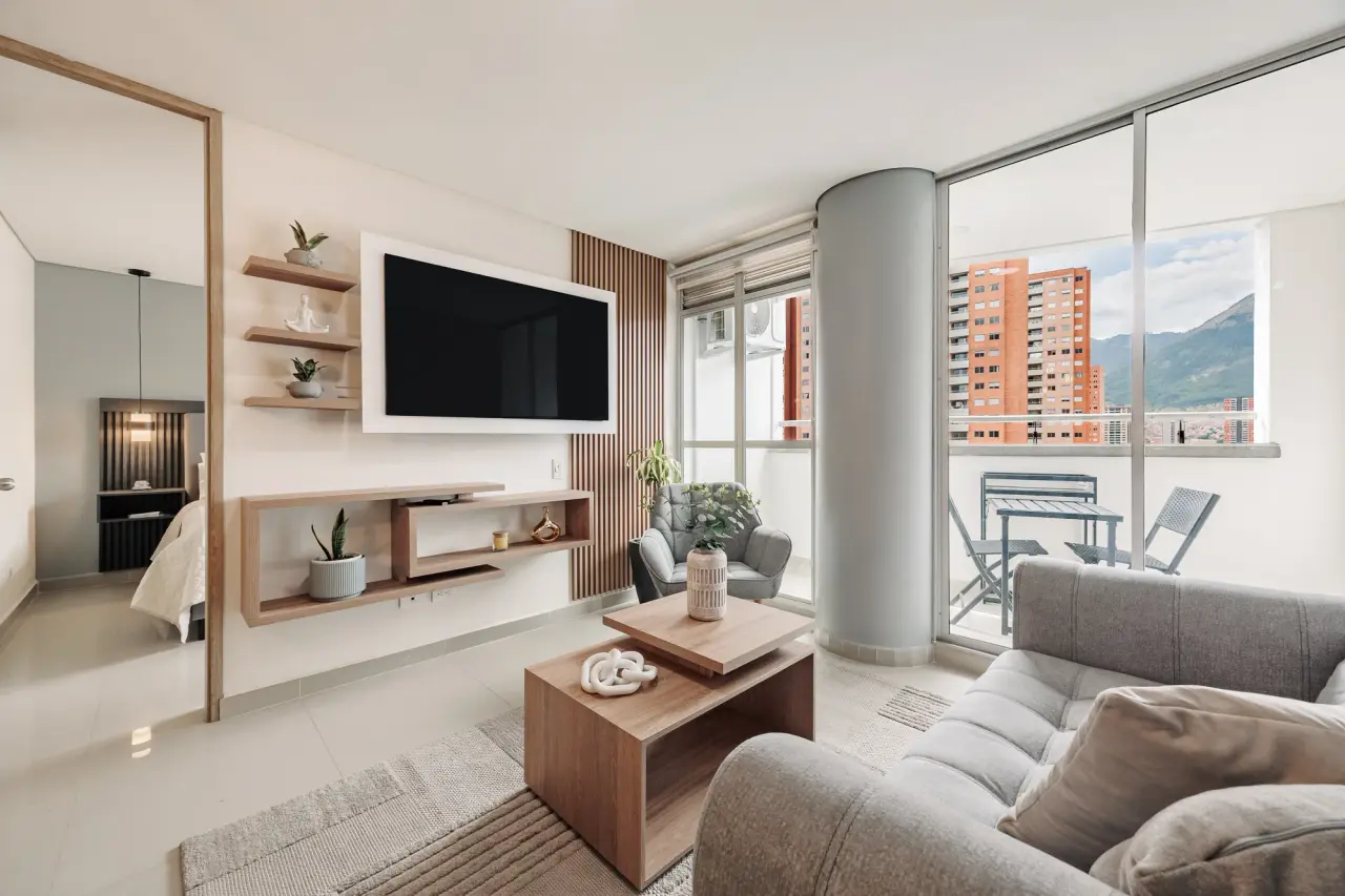 Living room with a wall-mounted TV, oak shelving and the balcony beyond