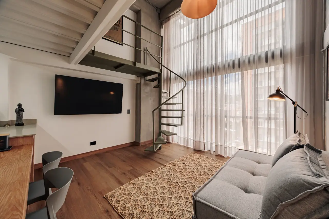Living room under the double-height curtains, with the TV and the spiral stair