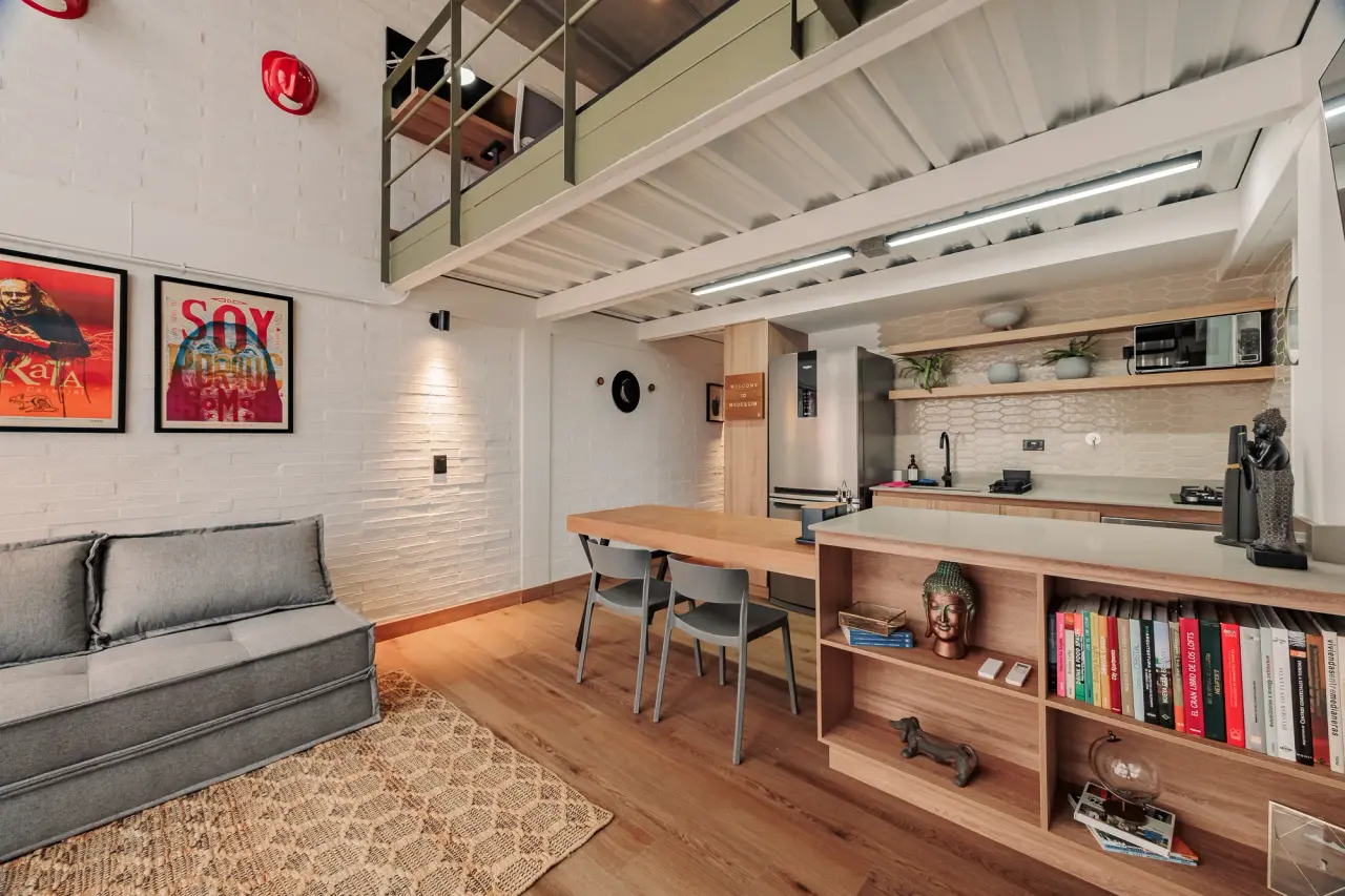 Sofa, dining table and the low bookshelf, under the framed prints on white brick