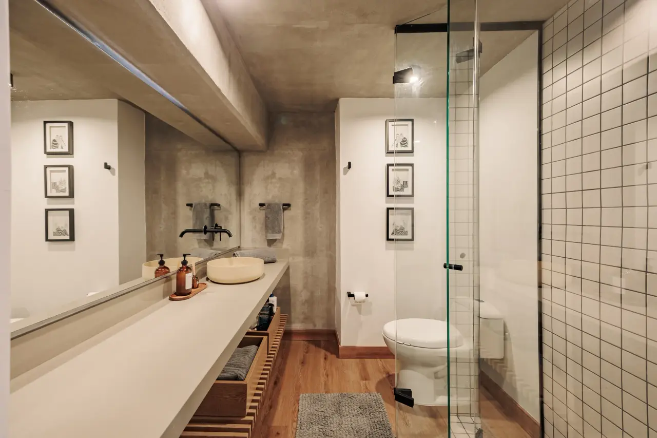 Bathroom with a long vanity, walk-in shower and the loft window beyond