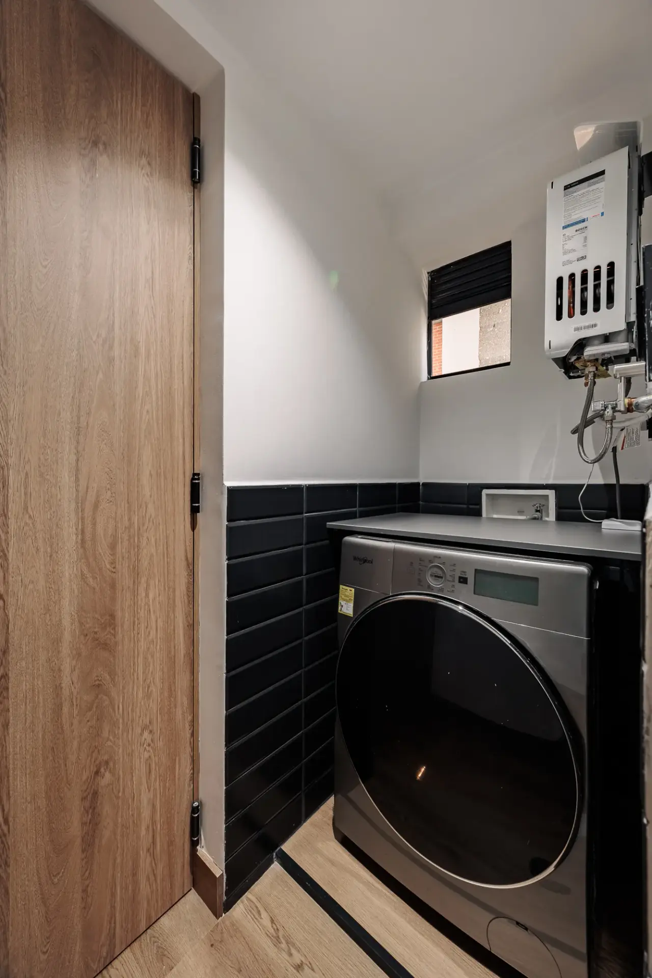 Washer and dryer in their own black-tiled utility nook