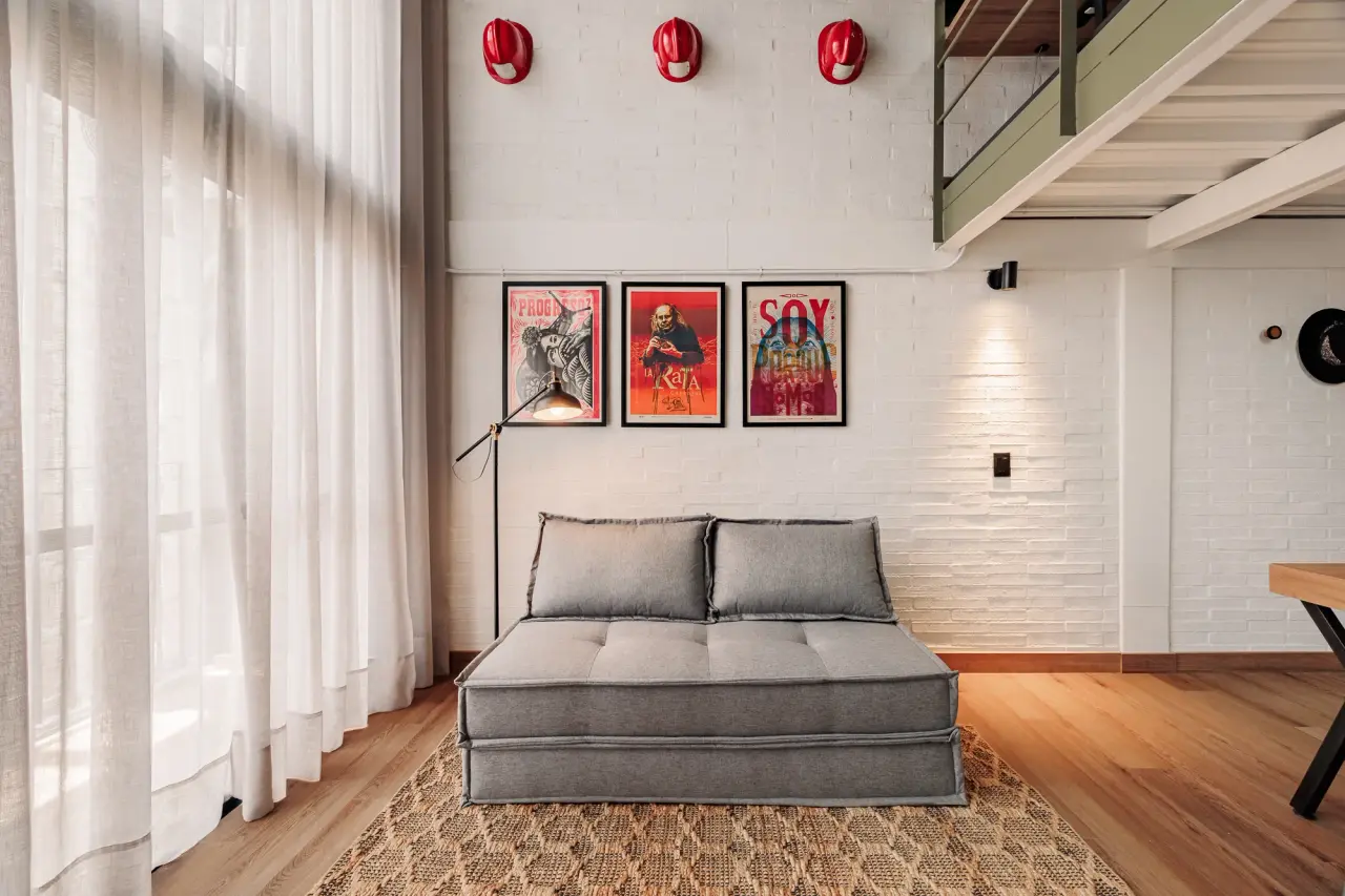The sofa bed below the framed prints, beside the full-height curtains